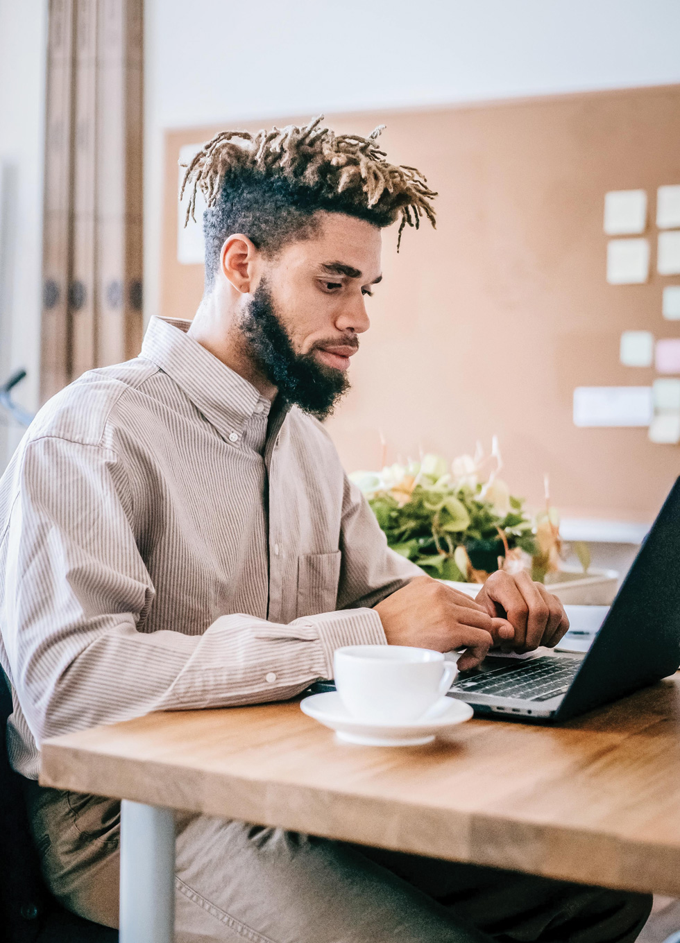 An invidiaul working remotely at a coffee shop on a laptop computer.