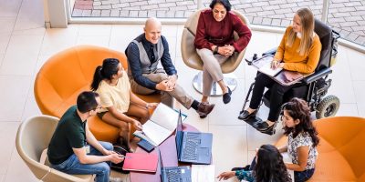 A group of co-workers meeting together, in person, at work.